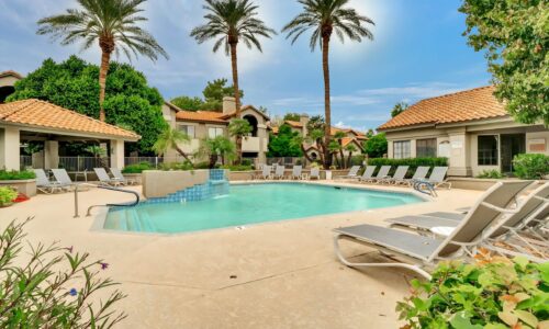 Presidio Condominiums community pool & spa with mature landscaping and the clubhouse in the background.